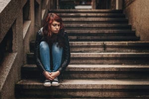 Depressed teenager sitting lonely outdoors