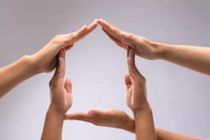 Hands of family members forming house shape