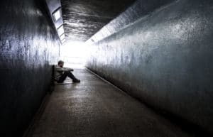Young homeless adult male sitting in subway tunnel
